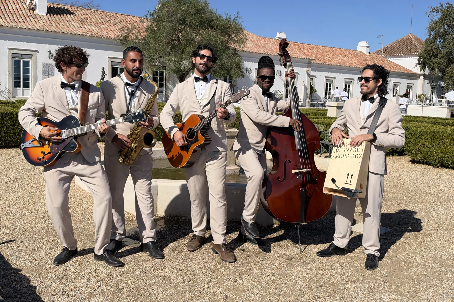 The Keys Roaming Band five-piece with guitar, saxophone, double bass and cajon in a palace garden