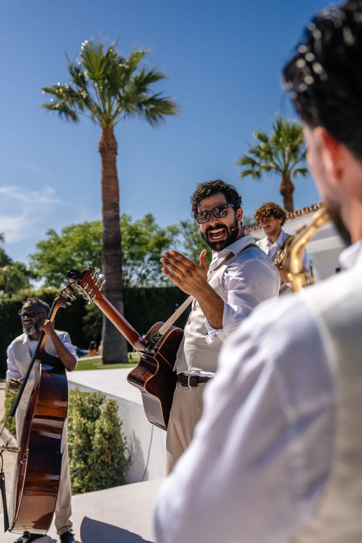 Saxophonist and band performing outdoors under palm trees