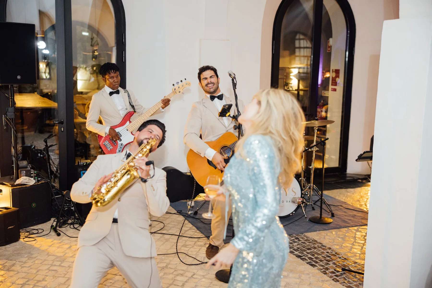The Keys Wedding Band in ivory suits playing with a dancing guest